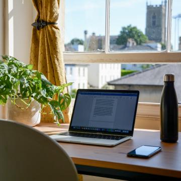 Laptop on a home desk in front of open window